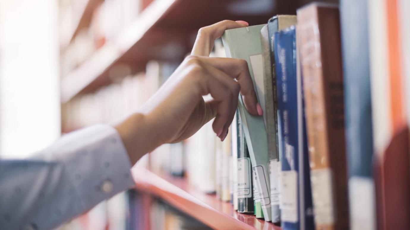 Student taking a book from a library shelf