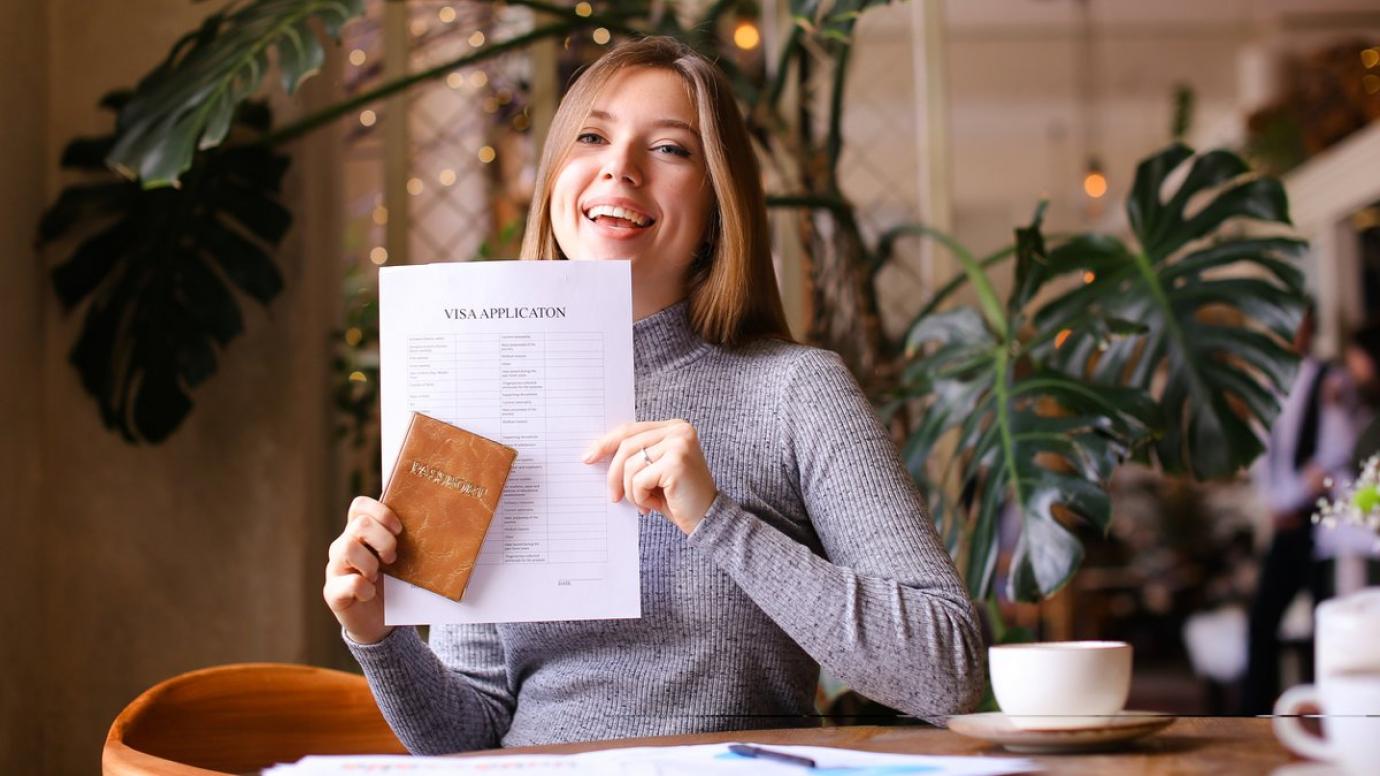 Happy woman holding a passport and visa application