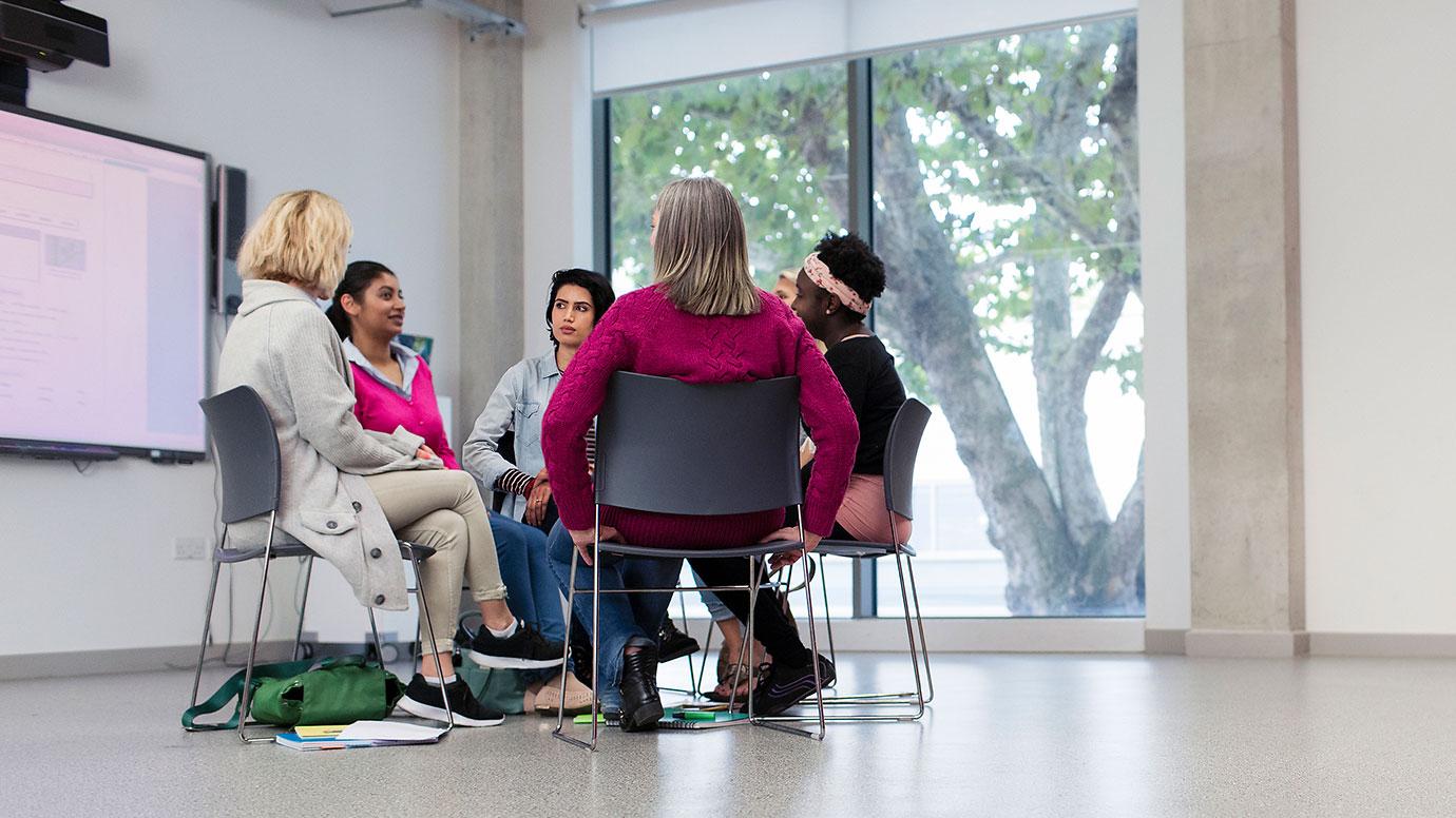 A group of female educators discussing in circle in a meeting room