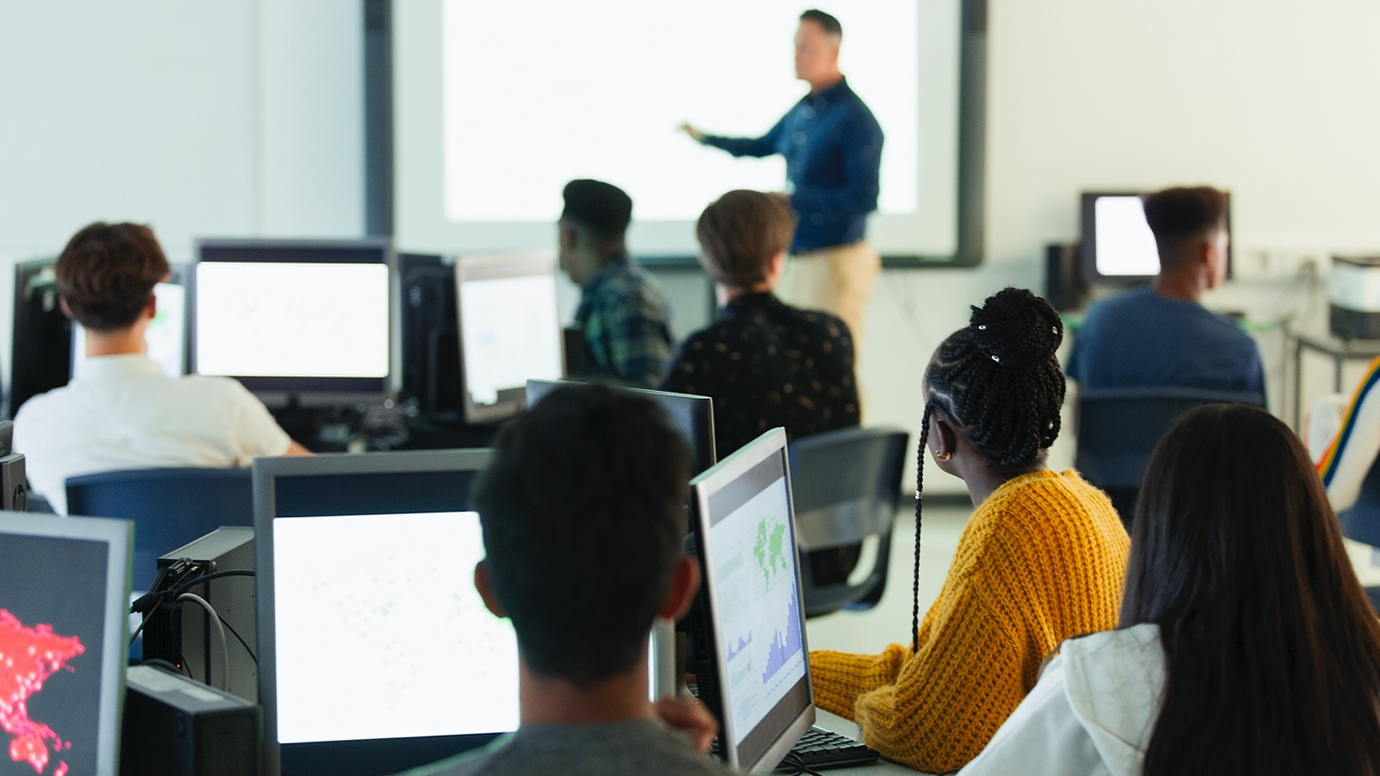 A group of students sitting in front of their computers in an IT related class