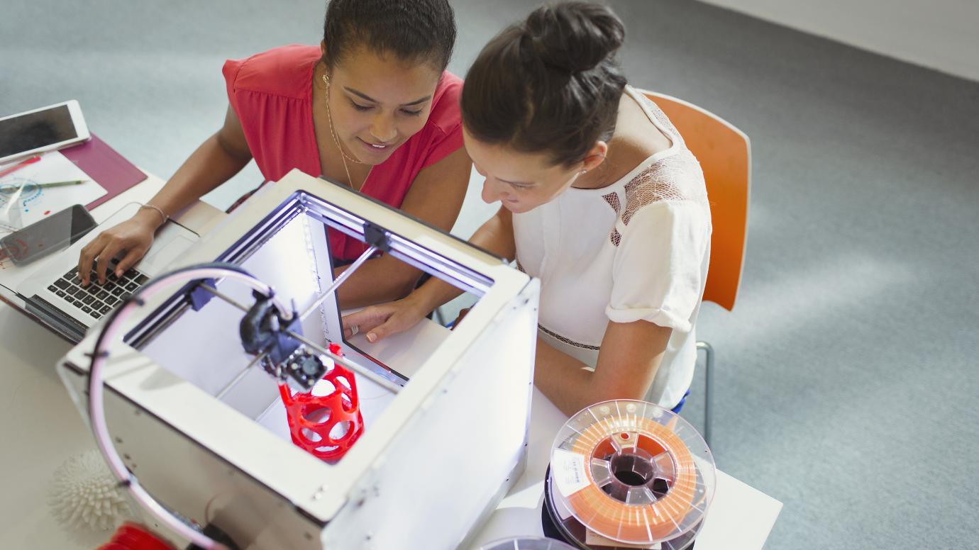 Two women working together with a laptop and a 3D printer