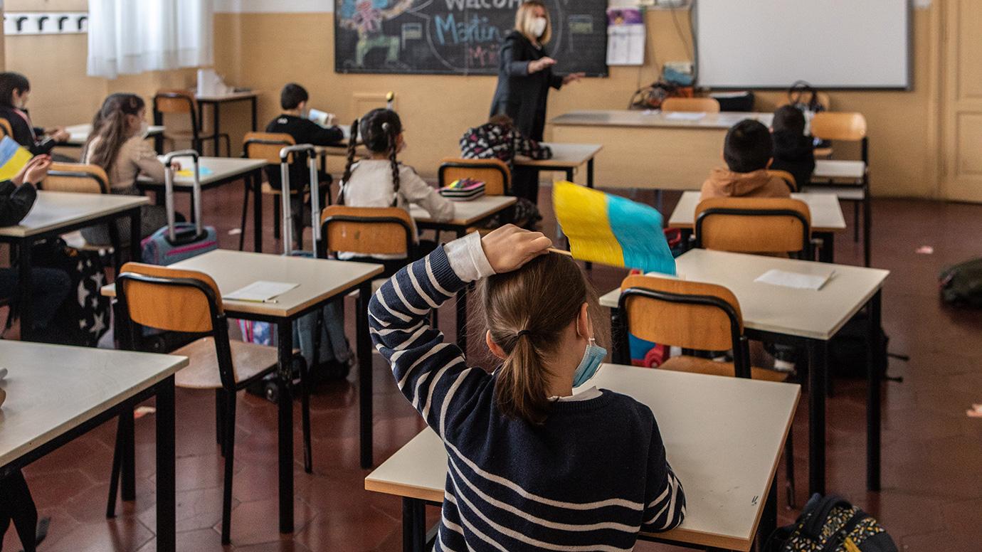 Primary students waving small self-made Ukrainian flags in class