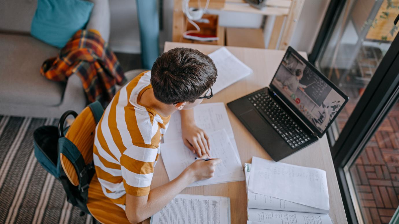 Teenage boy attending a remote class from home during COVID-19 lockdown