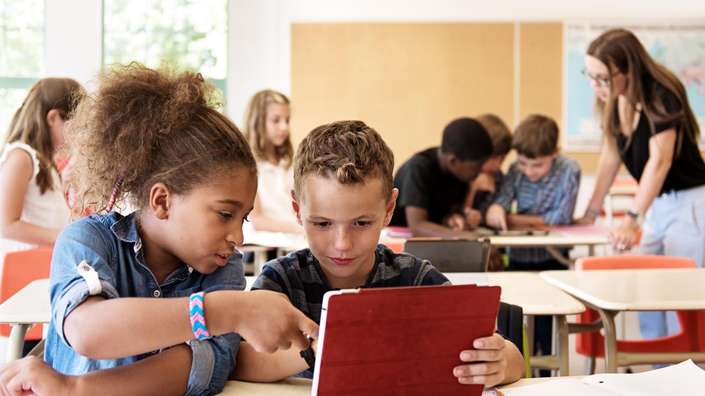 An ethnically diverse girl and boy working together on a tablet