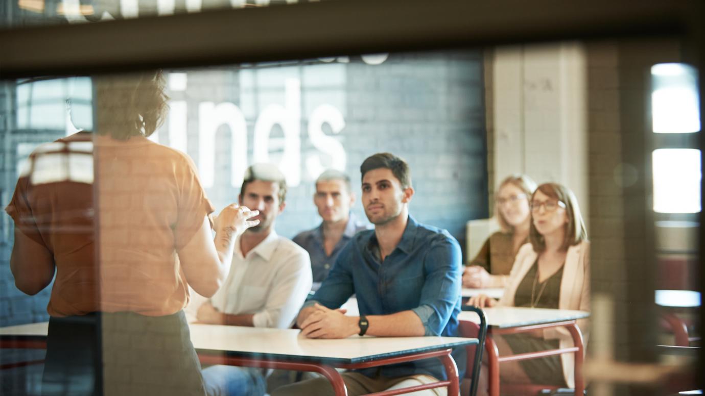 Multiple students sitting a in a classroom listening to teacher 