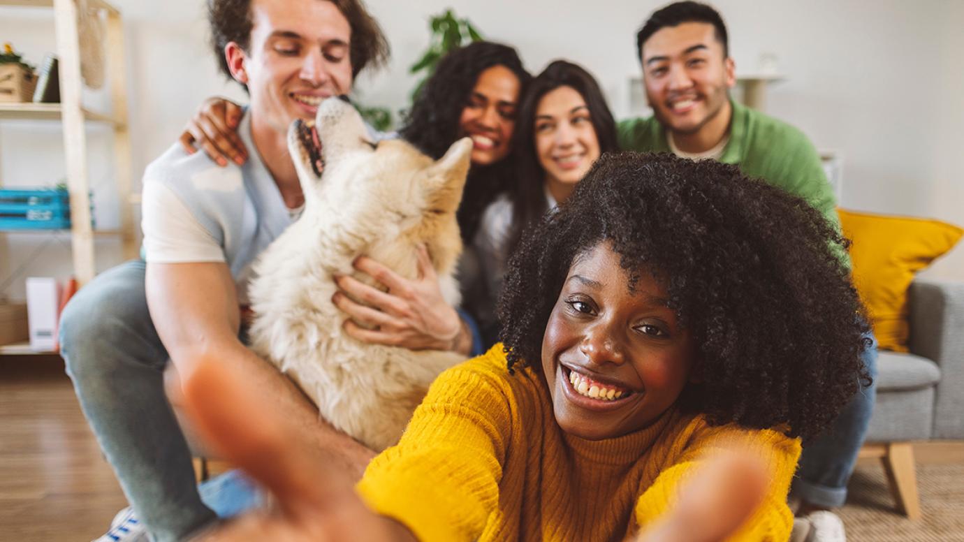 Multiracial group of young people taking a selfie with a dog