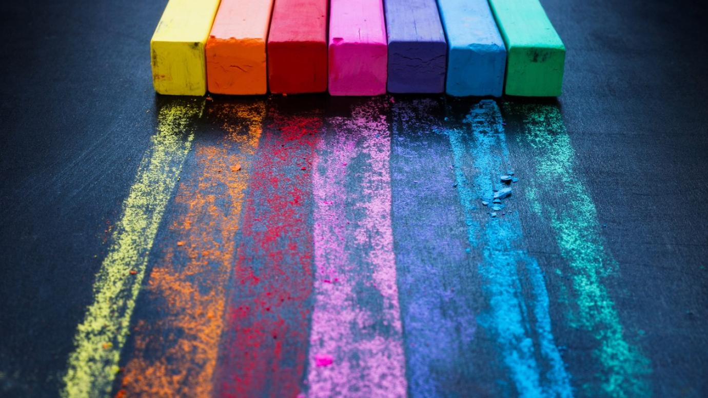 Colour crayons drawing a rainbow pattern on a black desk