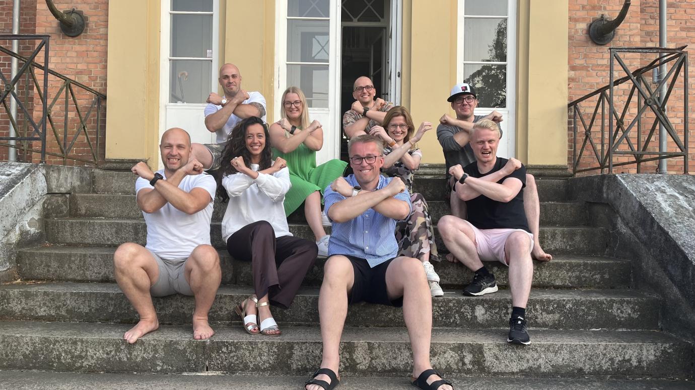 Group of members from various teams selected at the 2023 Accelerator Programme holding up their crossed arms and fists