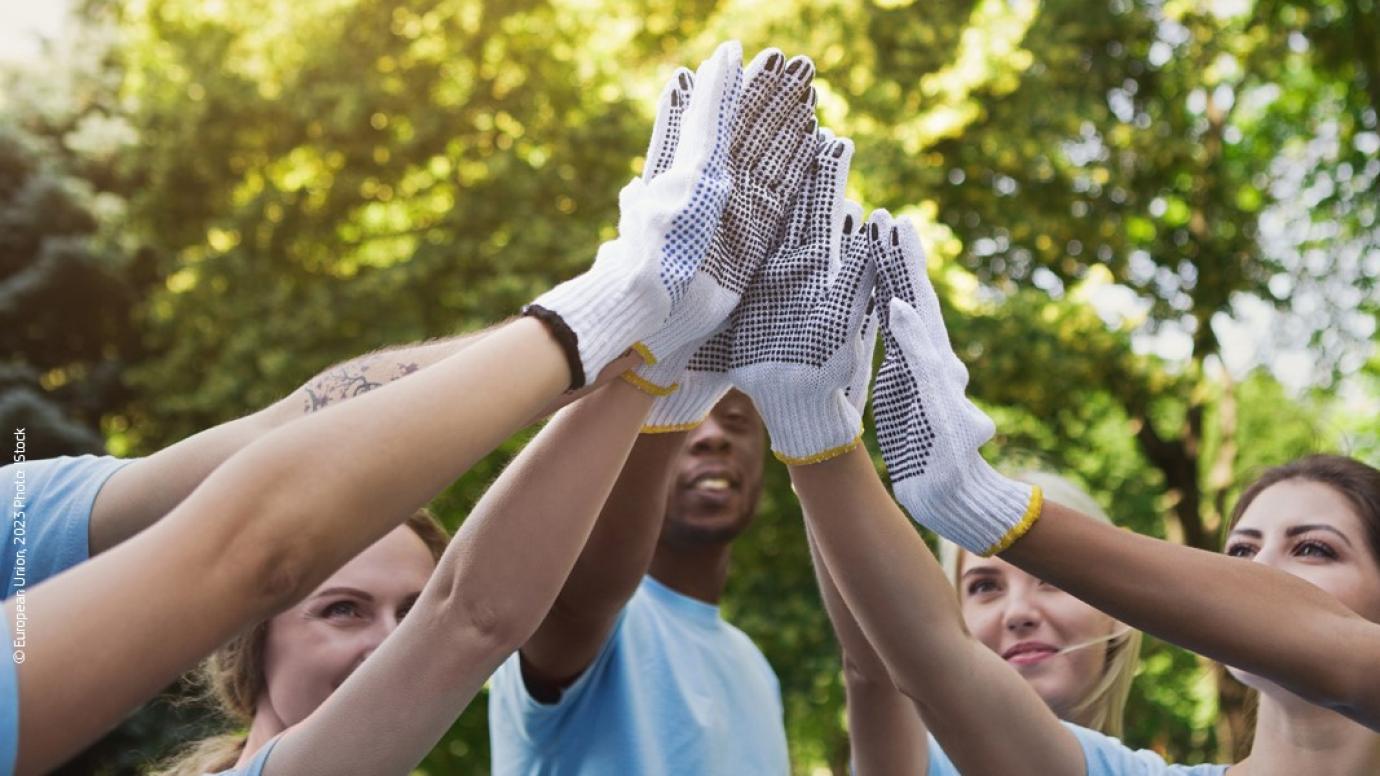 A group of young people outside with their hands together in the air
