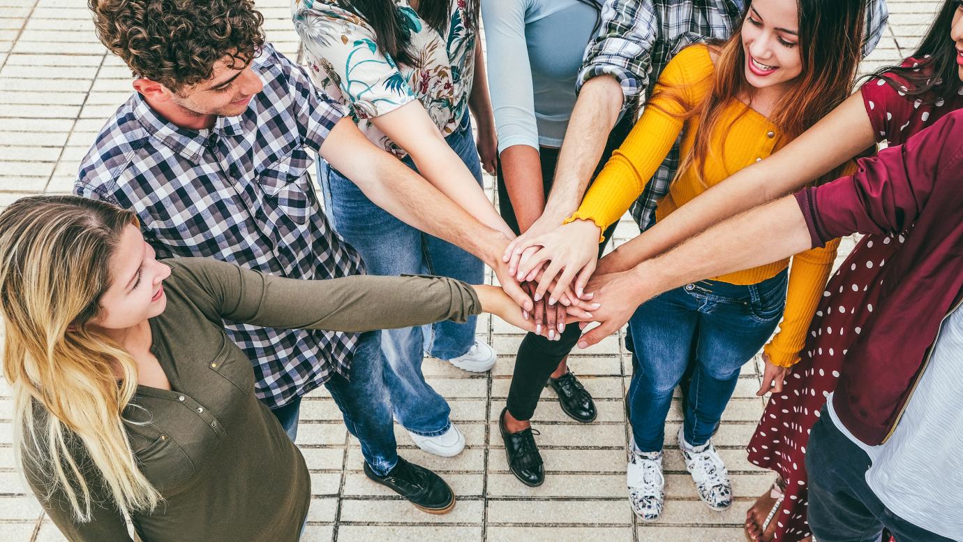 Young happy people stacking hands outdoor, focus on hands.