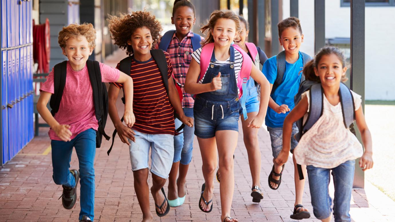 Group of diverse cheerful pupils running towards the camera