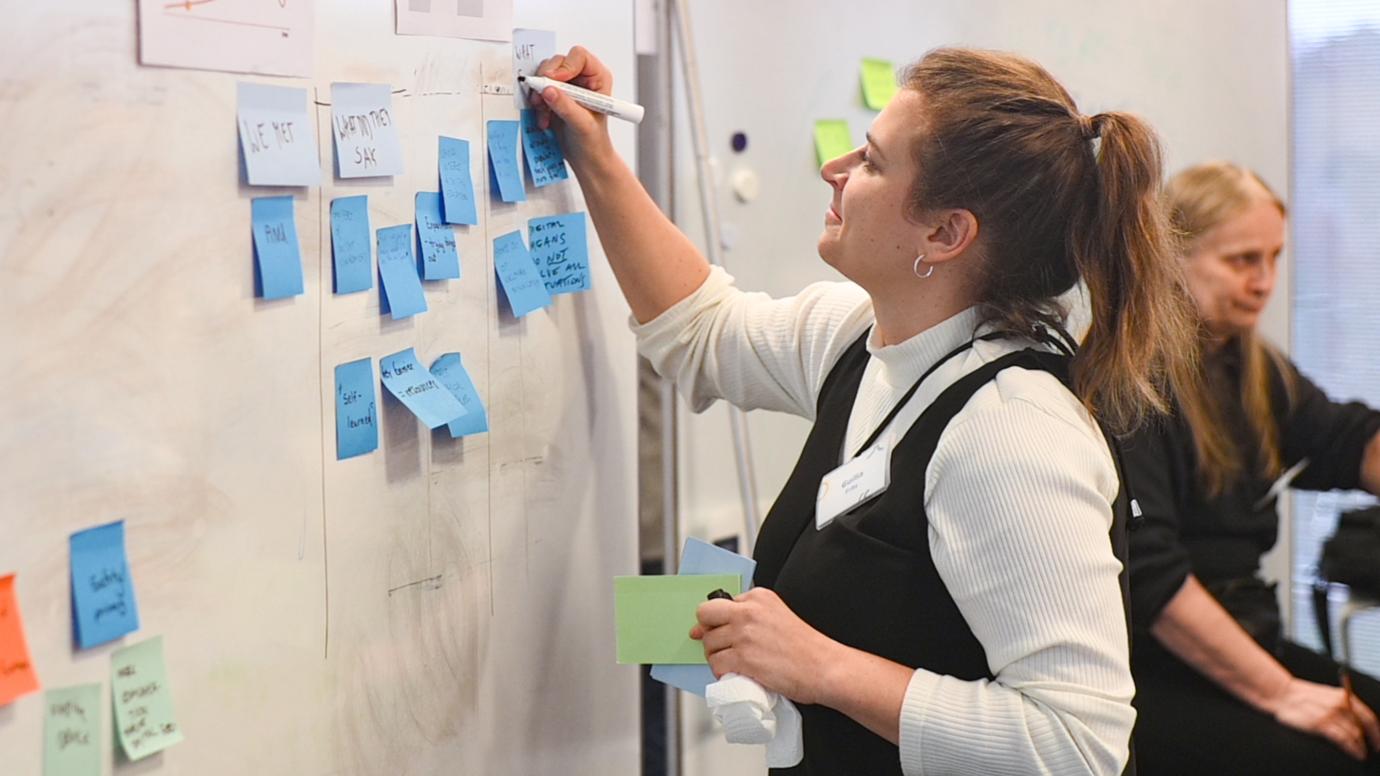 Woman writing ideas on white board during workshop