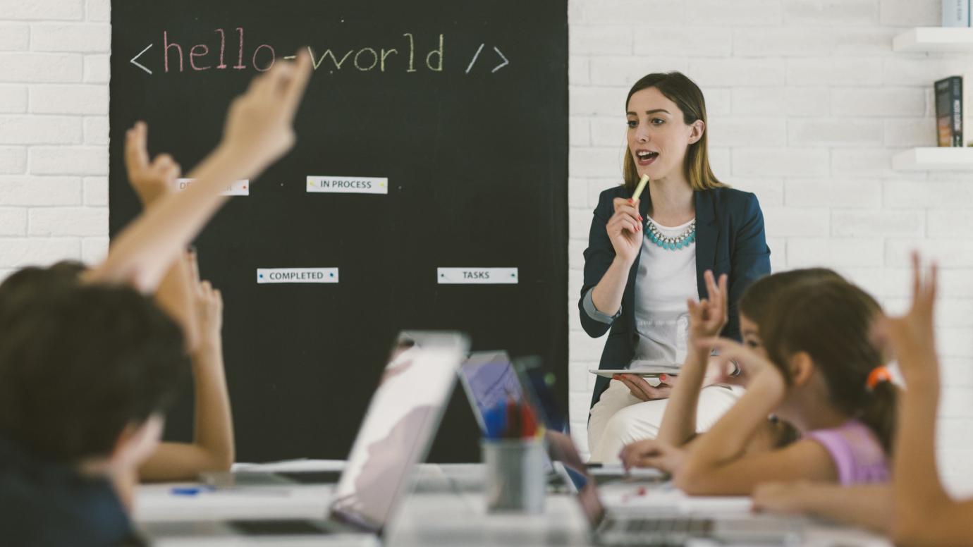 Teacher in front young students during coding class