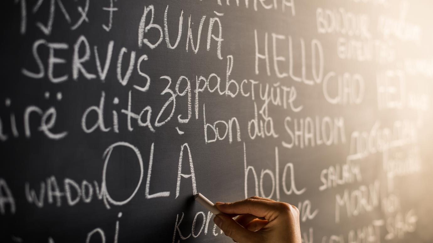 Hand writing on a blackboard the different words for "hello" in European languages