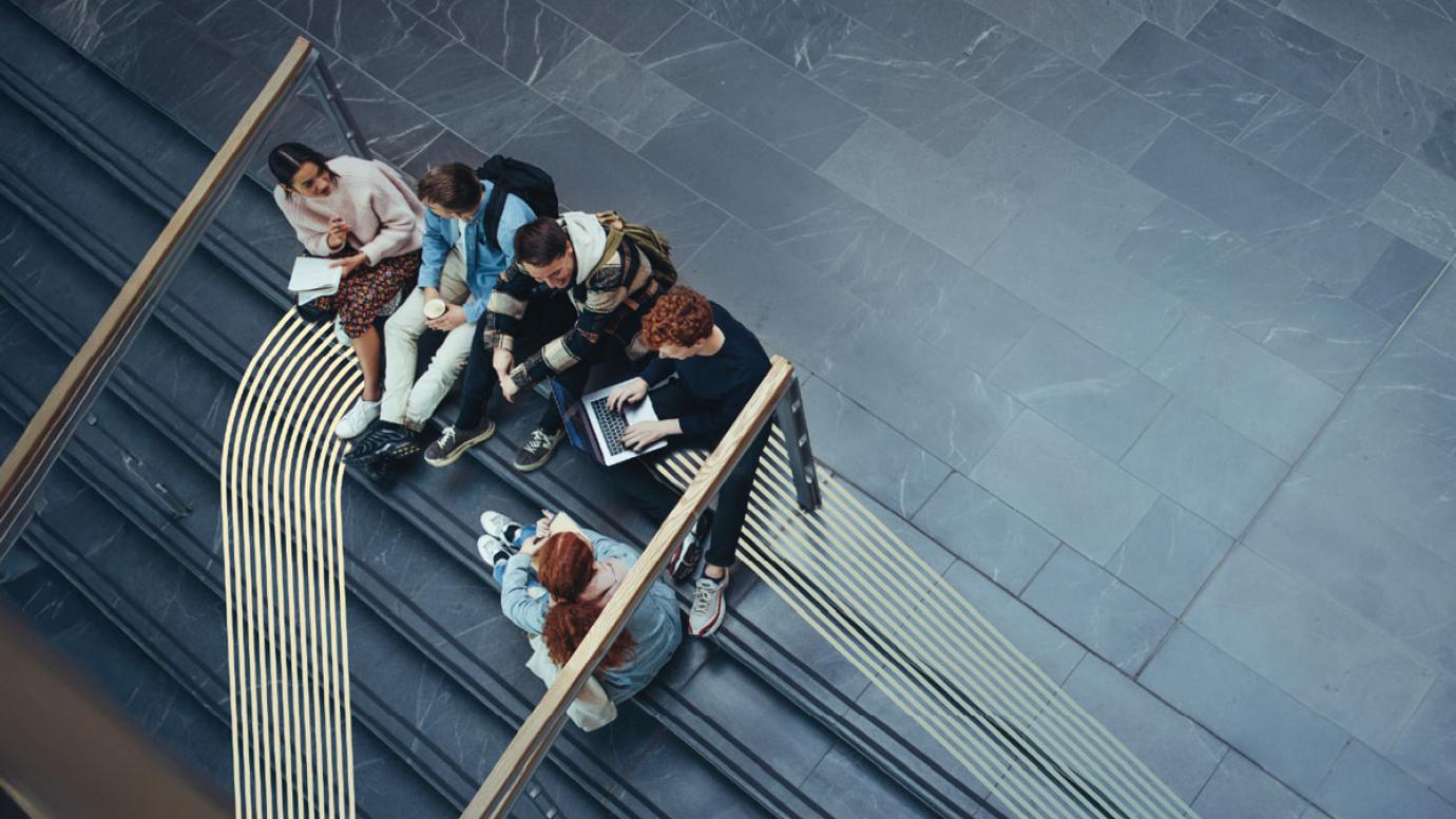 A group of young students sitting on the stairs at their campus, viewed from above